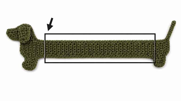 Crochet dachshund bookmark handmade with yarn, featuring a long body, short legs, floppy ear, and curly tail.