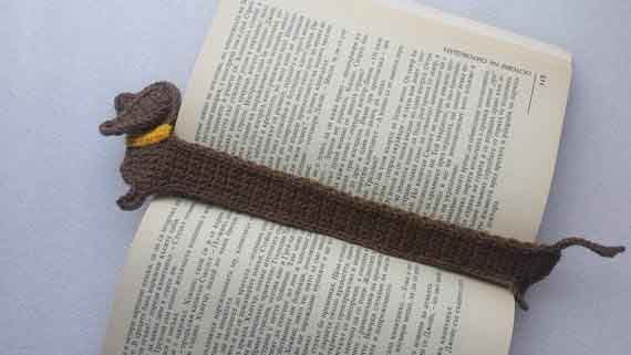 Crochet dachshund bookmark handmade with yarn, featuring a long body, short legs, floppy ear, and curly tail.
