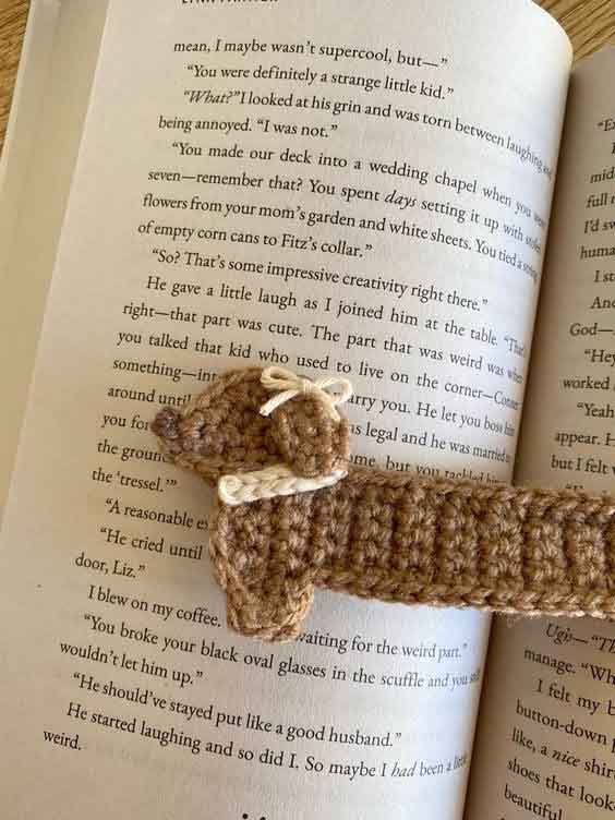 Crochet dachshund bookmark handmade with yarn, featuring a long body, short legs, floppy ear, and curly tail.